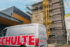 Schulte Bauunternehmen Servicefahrzeug vor Baustelle mit gelbem Kran und eingerüstetem Backsteingebäude